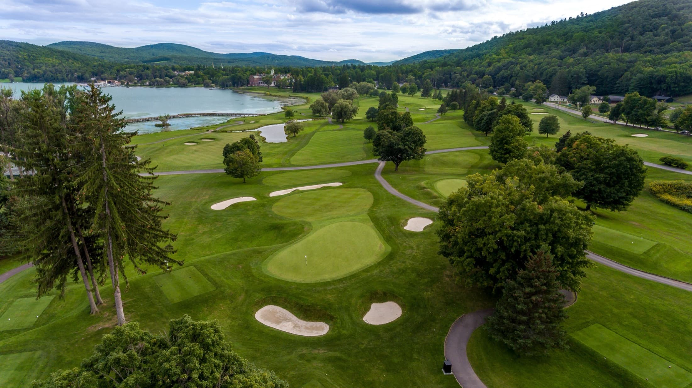 Aerial view of Leatherstocking Golf Course along the shore of Otsego Lake in Cooperstown, with the Otesaga Resort Hotel beyond the fairways