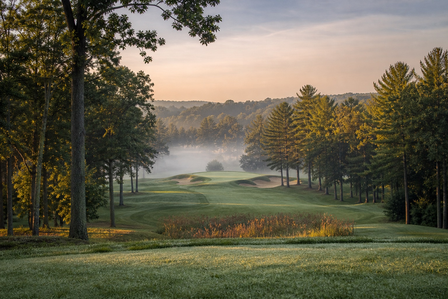 A classic parkland golf course at dawn with tall trees and deep bunkers